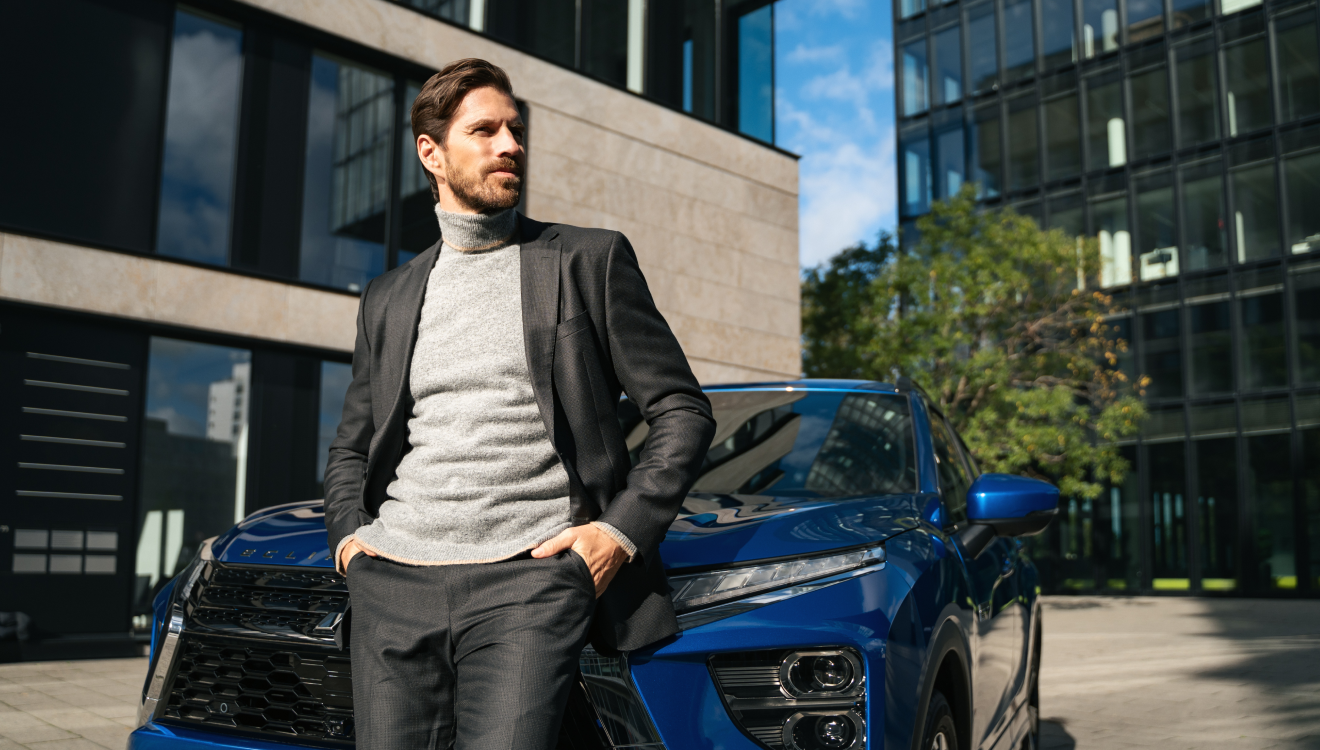 Homme à côté d'un véhicule Mitsubishi qui présente les offres pour professionnels